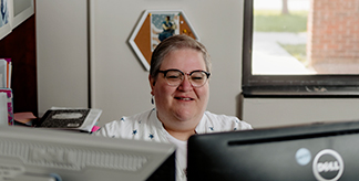 Anne Dugger looking at computer screens in office