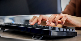 Two hands on a computer keyboard.