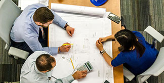 An areal image of three people collaborating at a desk