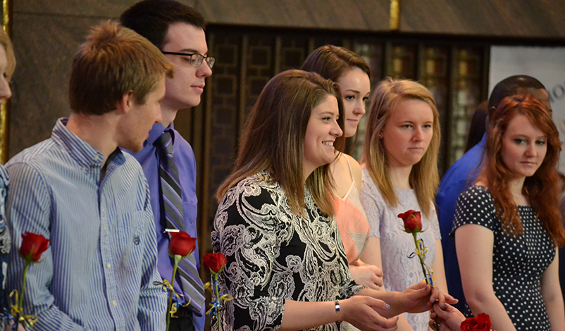 A student receiving a rose during commencement mass