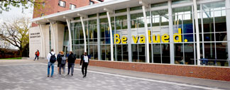Image of the MMU University Center with a sign on the window saying be valued.