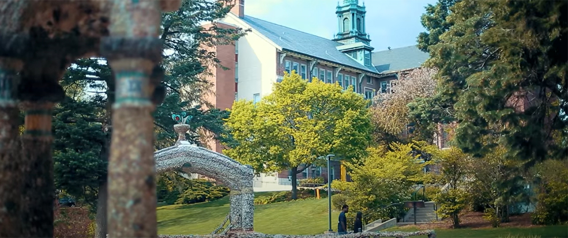 Two students walking through the grotto in front of Warde Hall