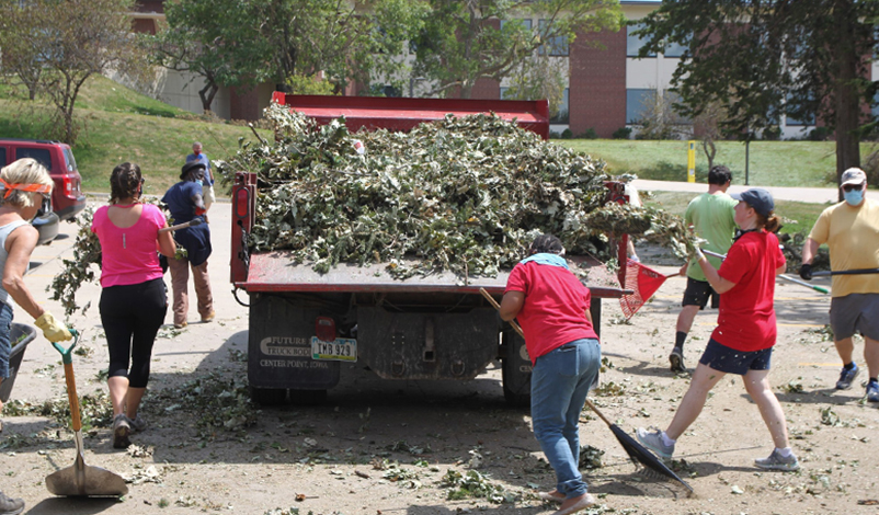 A group of people loading loose branches into a truck