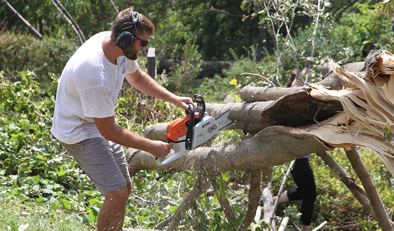A man clearing branches with a chainsaw