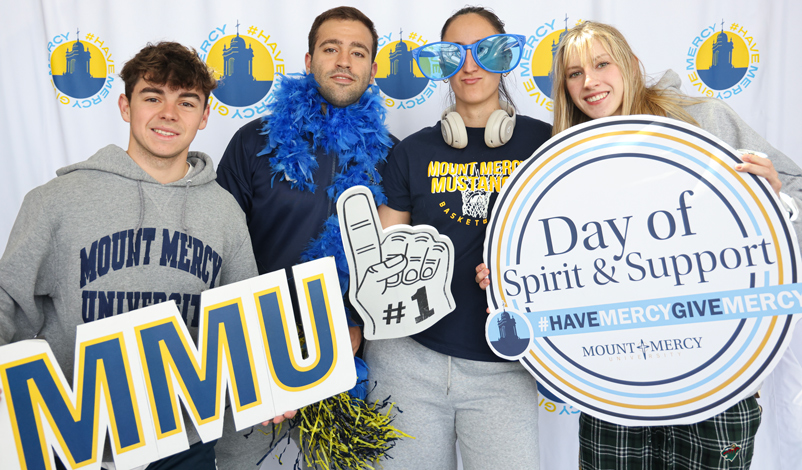 Students posing for a photo with mmu signs