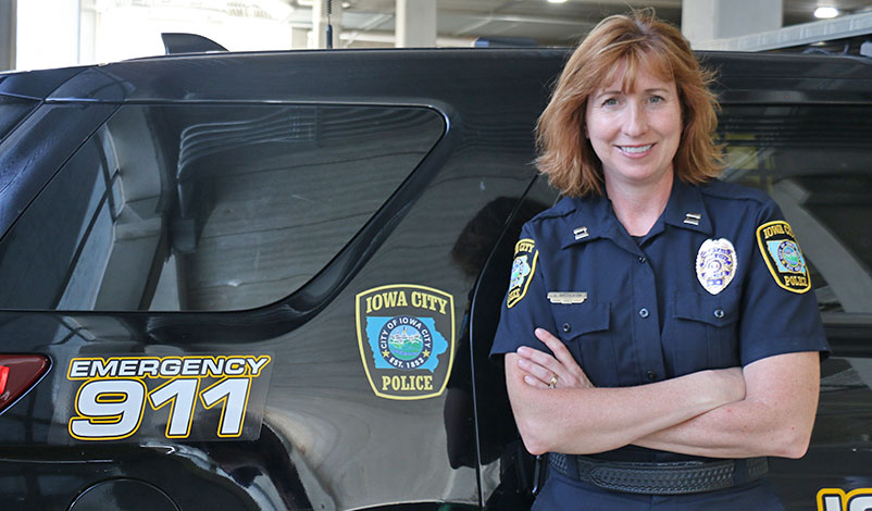 Denise, standing in front of an ICPD police vehicle