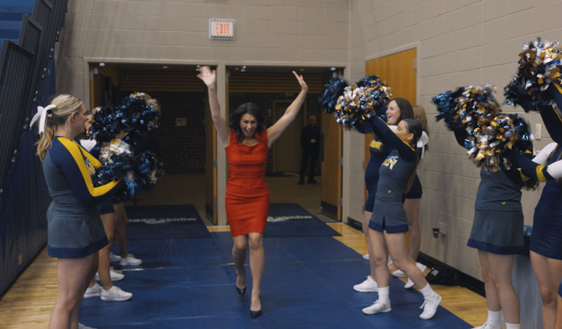 Stefanie Munsterman, Mount Mercy alumni award recipient, running through cheerleaders with her arms raised