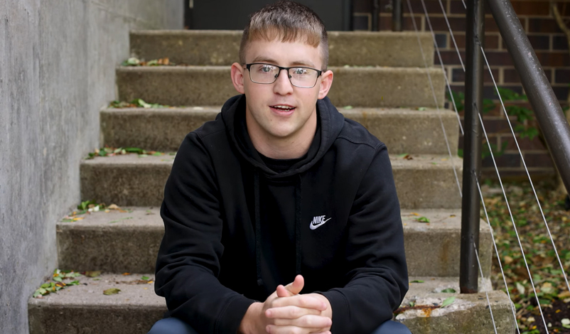 Jacob Perks, sitting outside the Hennessey Gym at Mount Mercy