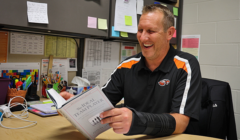 Brad, reading "The Ideal Team Player" and smiling at his desk