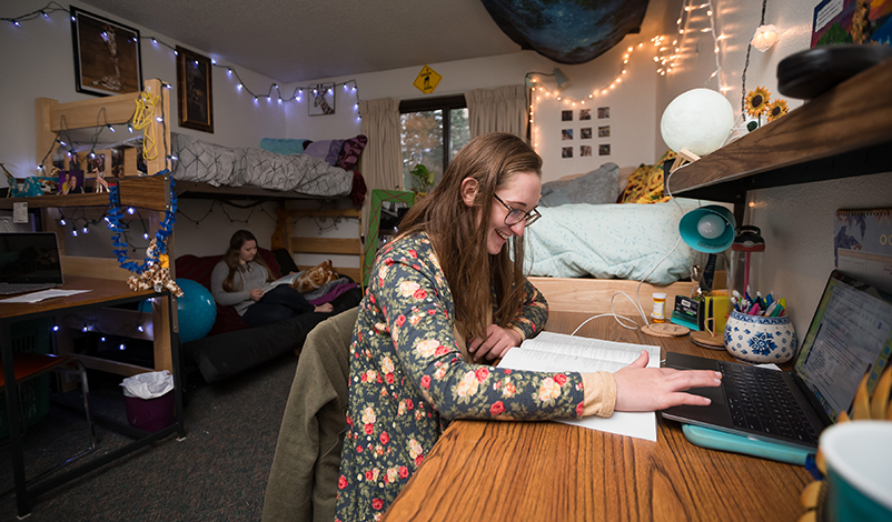 A student in her dorms, sitting at a desk