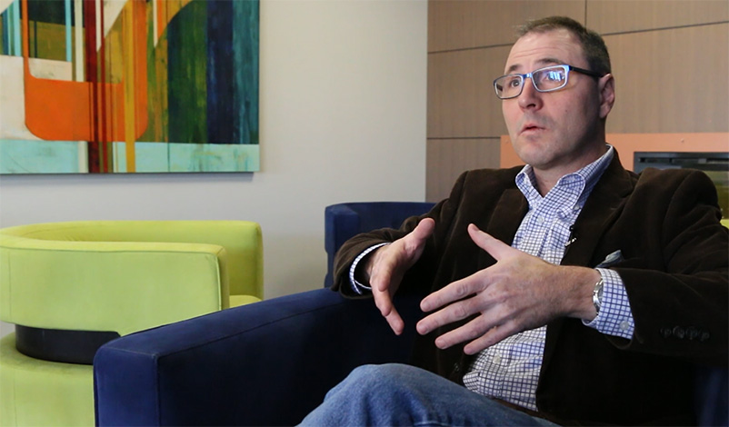 Mark Latta, sitting in a chair at the Mount Mercy graduate center and talking