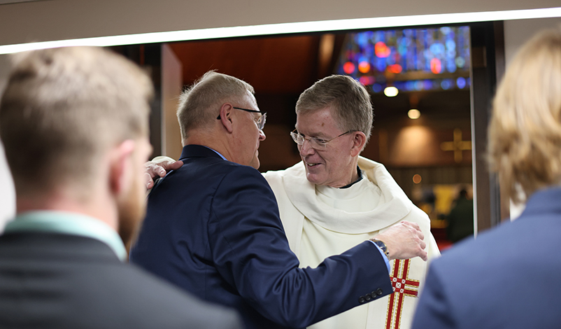 President Olson embracing the reverend during Mass