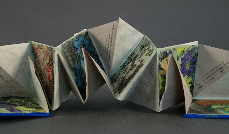 A folded printmaking work with text and floral drawings