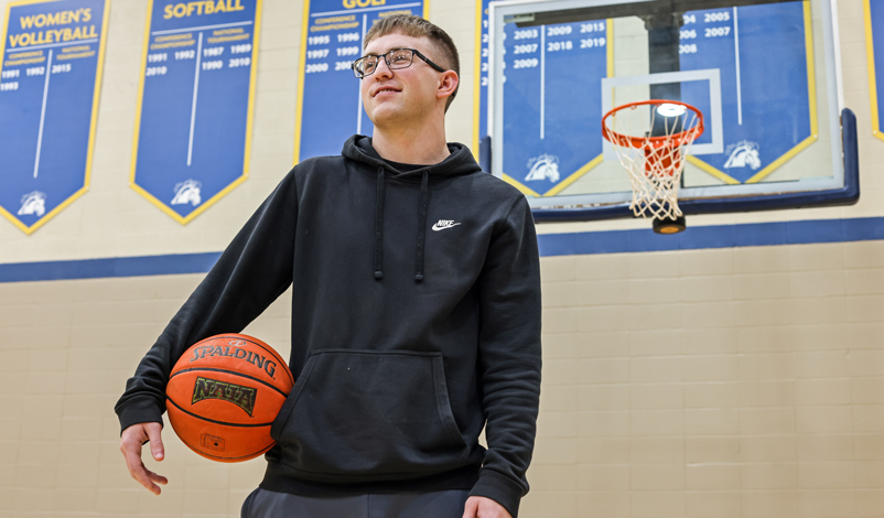 Jacob Perks, posing with a basketball in the Hennessey Gym