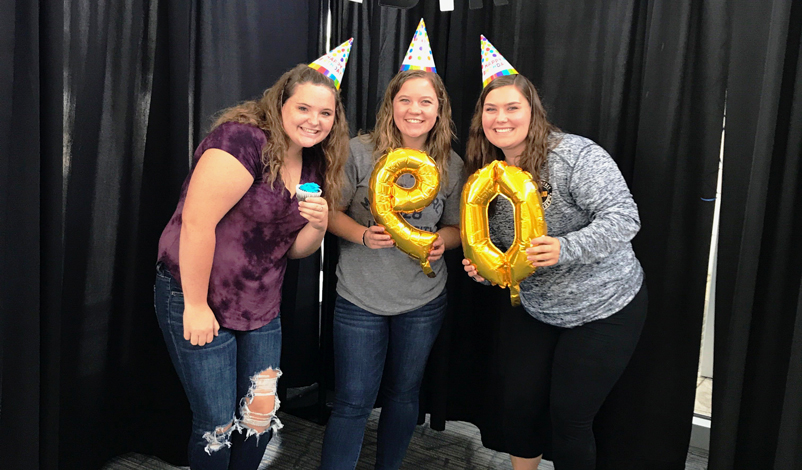 Macey and friends posing with 90 balloons for the university's anniversary