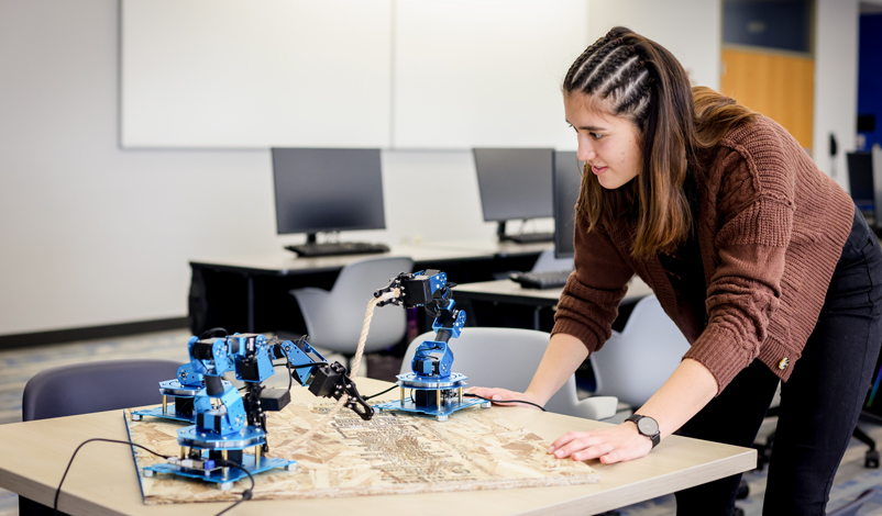 Nathalie Primbs '25 observing robotic arms in the middle of Basile Hall's Data Science computer lab