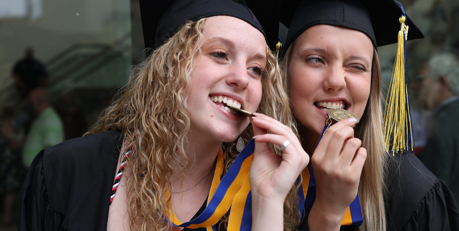 two students posing with their commencement medals