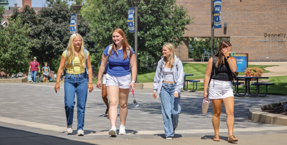 Four students walking on MMU classes with backpacks