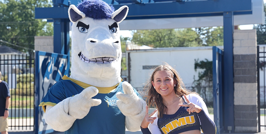 Mustang Sally mascot and cheerleader pose with peace signs for picture