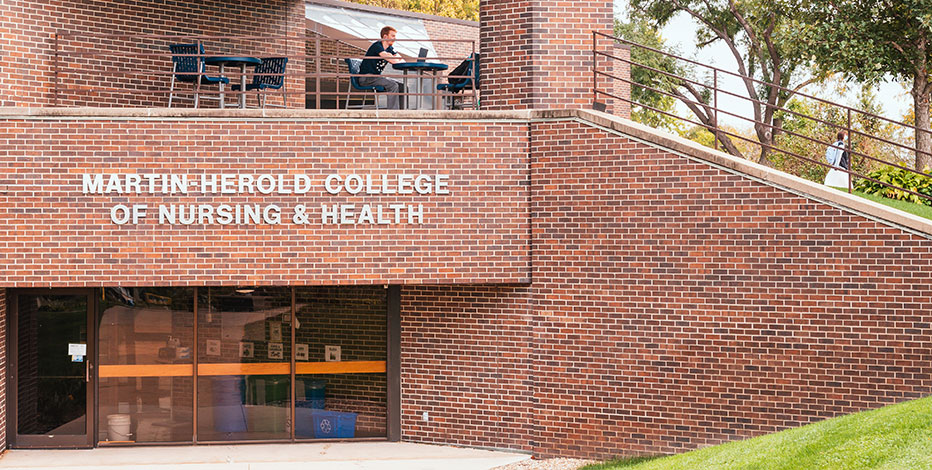 A student studying outside of the matrin Herold College of Nursing and Health