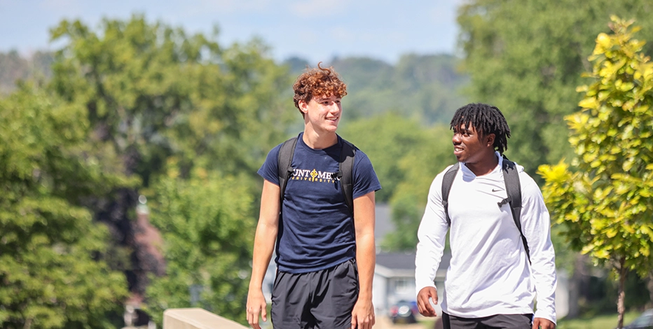 Two students walk and talk together on a sunny day on Mount Mercy University's campus.