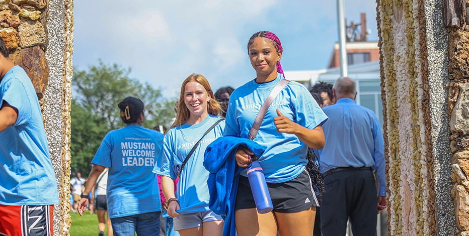 New students walk together and smile at the camera on Mount Mercy University's campus.