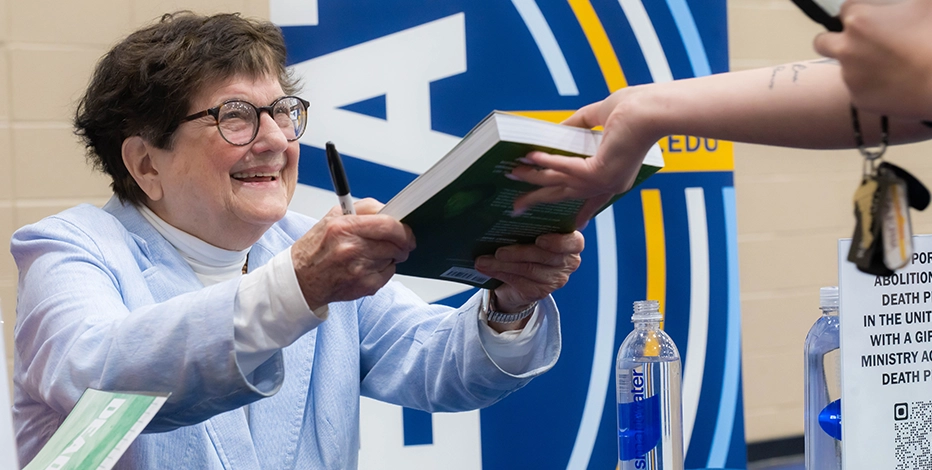 Sister Helen Prejean smiles as she receives a copy of her book "Dead Man Walking" to sign at Mount Mercy University.